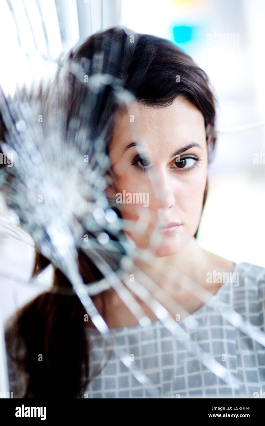 Femme malheureuse en face d'un miroir brisé. Banque D'Images