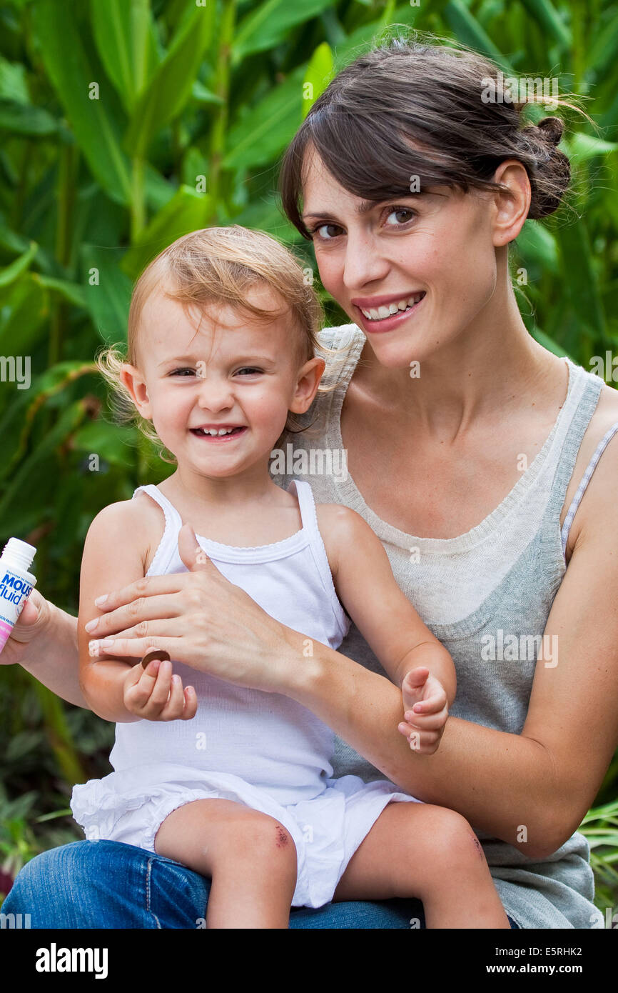 Mère d'appliquer une crème anti-moustique sur la peau de son bébé âgé de 20 mois. Banque D'Images