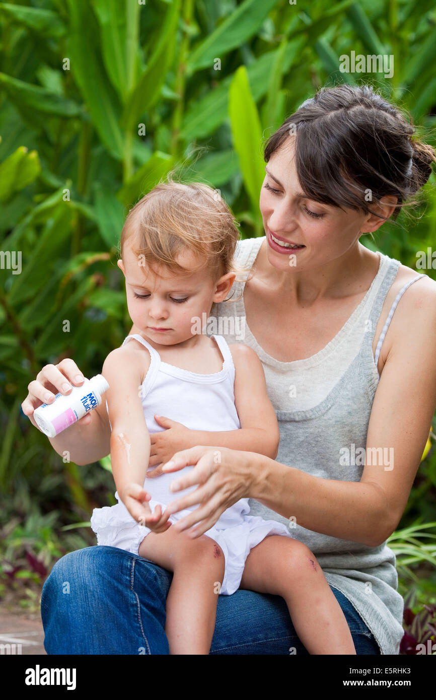 Mère d'appliquer une crème anti-moustique sur la peau de son bébé âgé de 20 mois. Banque D'Images