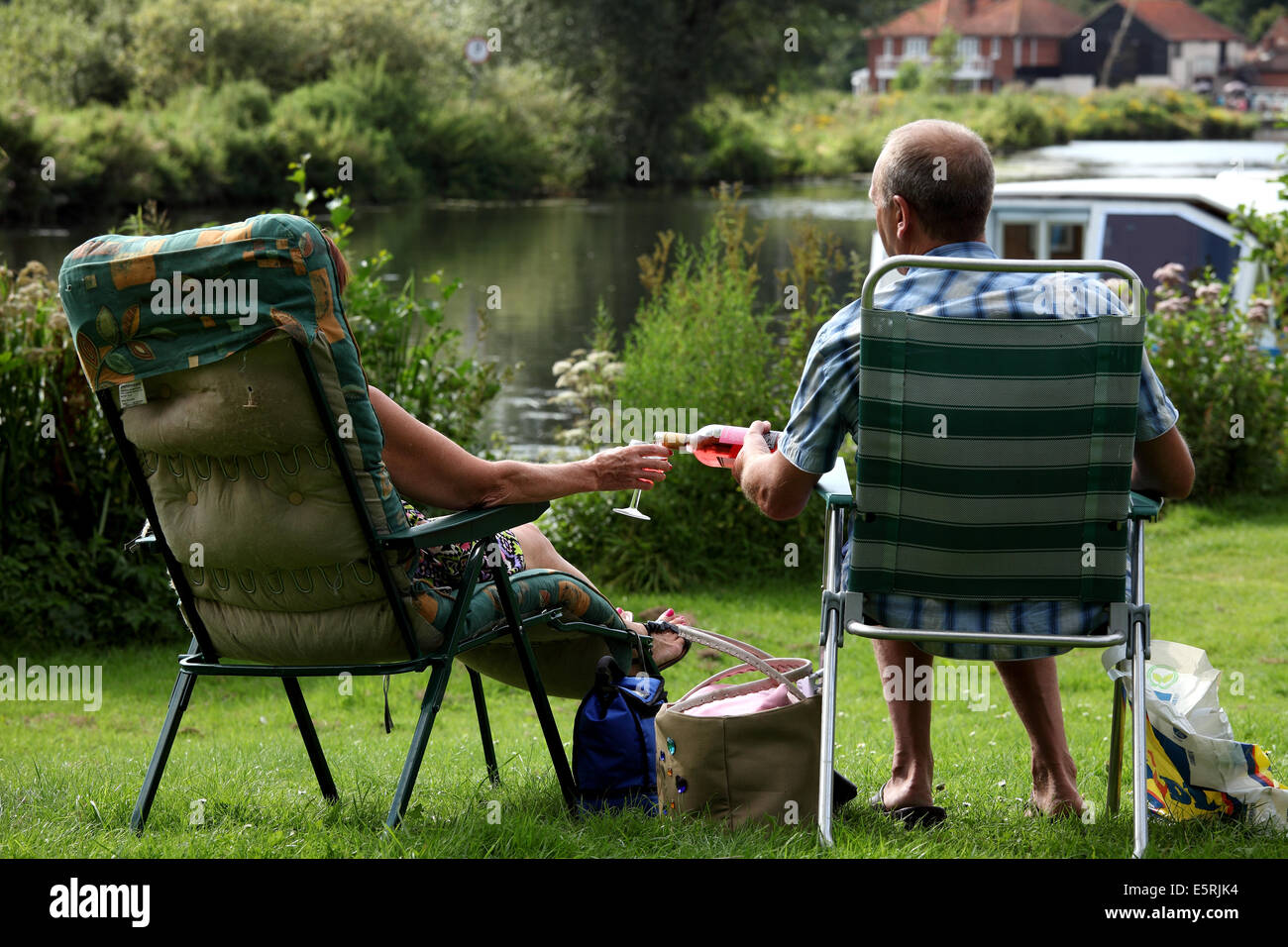 Un couple âgé fait une pause ensemble et pique-nique et un verre de vin rosé le long des Norfolk Broads sous le soleil d'été. Prise au village de Coltihad, Norfolk, Royaume-Uni. Banque D'Images
