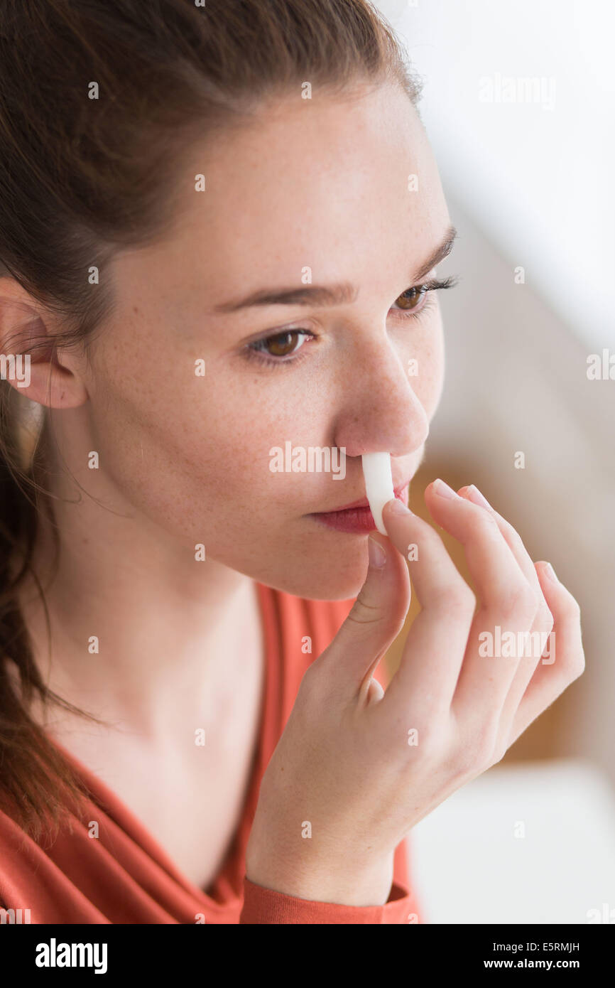Femme à l'aide d'une gaze stérile imbibé de peroxyde d'hydrogène pour arrêter un saignement de nez. Banque D'Images