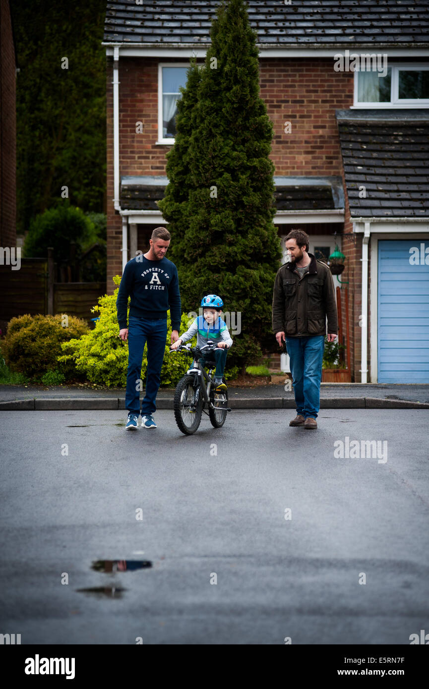 Apprendre à faire du vélo garçon vélo avec les parents de sexe masculin Banque D'Images