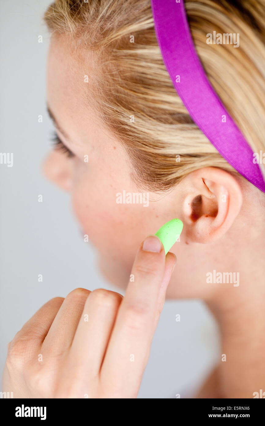 Femme portant des bouchons d'oreille. Banque D'Images