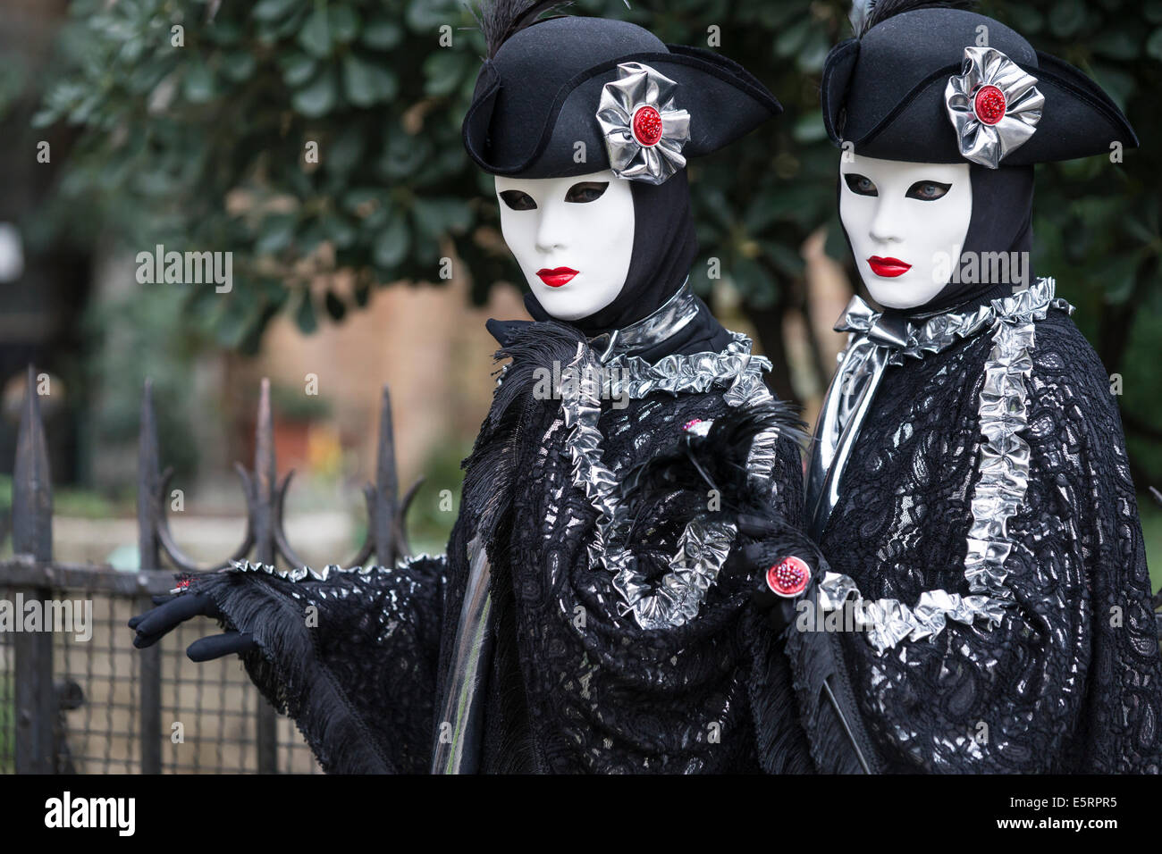 2 femmes en costumes du xviiie siècle stylisés identiques de noir avec de l'argent par l'église San Zaccaria pendant le Carnaval de Venise. Banque D'Images