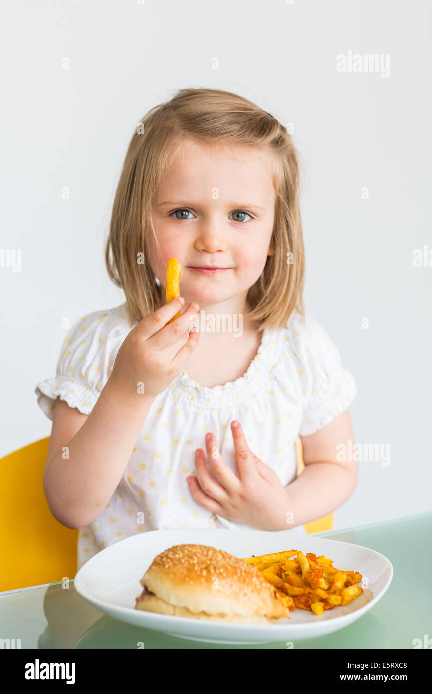 Fillette de 3 ans mangent des frites et un hamburger. Banque D'Images