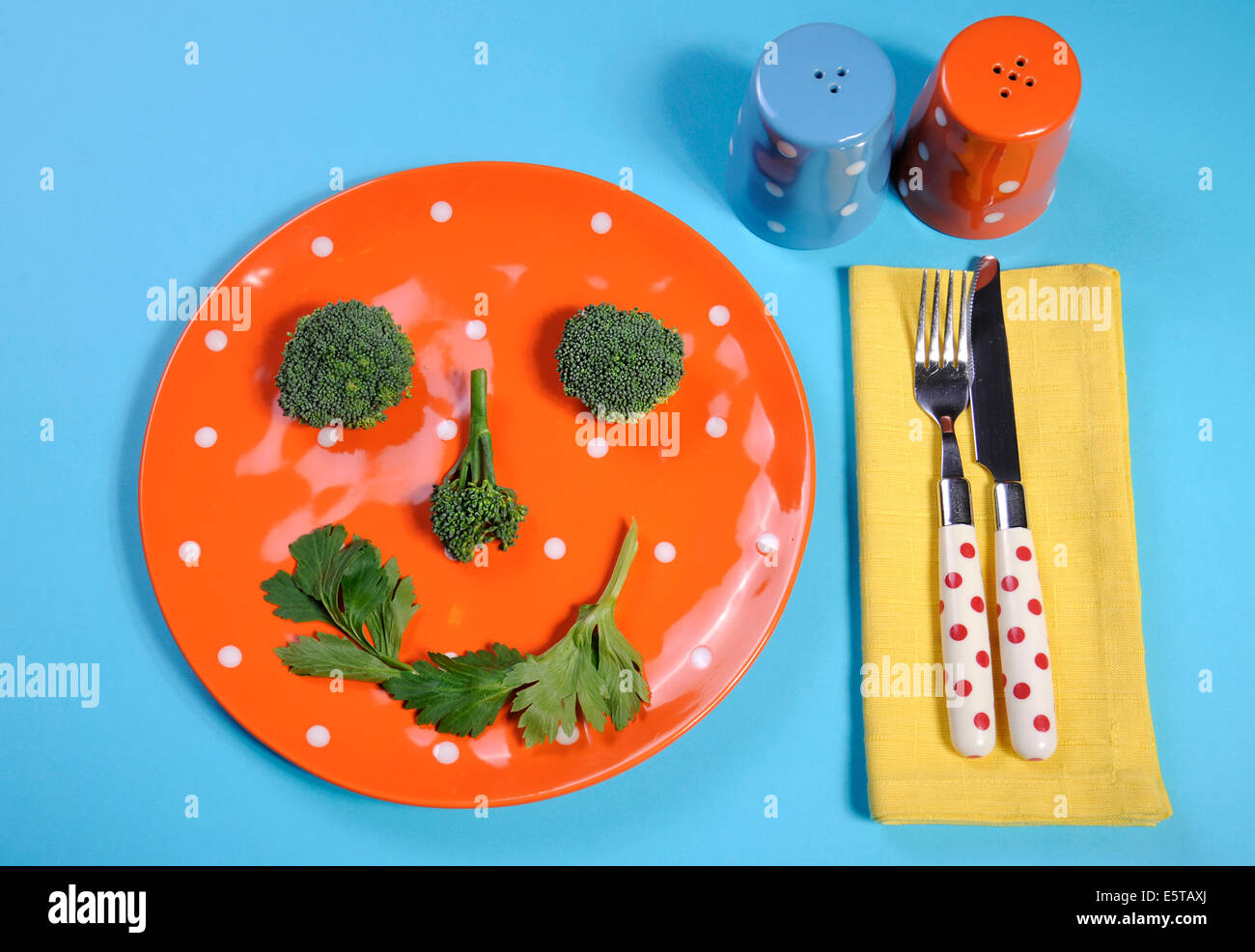 Alimentation saine alimentation santé concept avec heureux smiley fabriqués à partir de le brocoli et le céleri sur une plaque orange à pois Banque D'Images