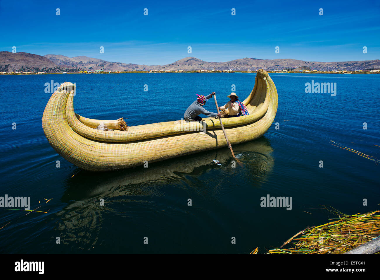 Deux personnes locales l'aviron bateau traditionnel fait de Totora roseaux sur le lac Titicaca, le sud du Pérou, Pérou Banque D'Images