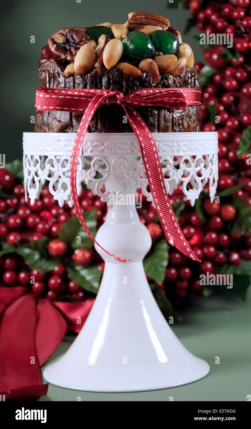 La nourriture de Noël, un gâteau aux fruits avec les cerises glacées et les écrous sur white cake stand avec maison de vacances berry wreath Banque D'Images