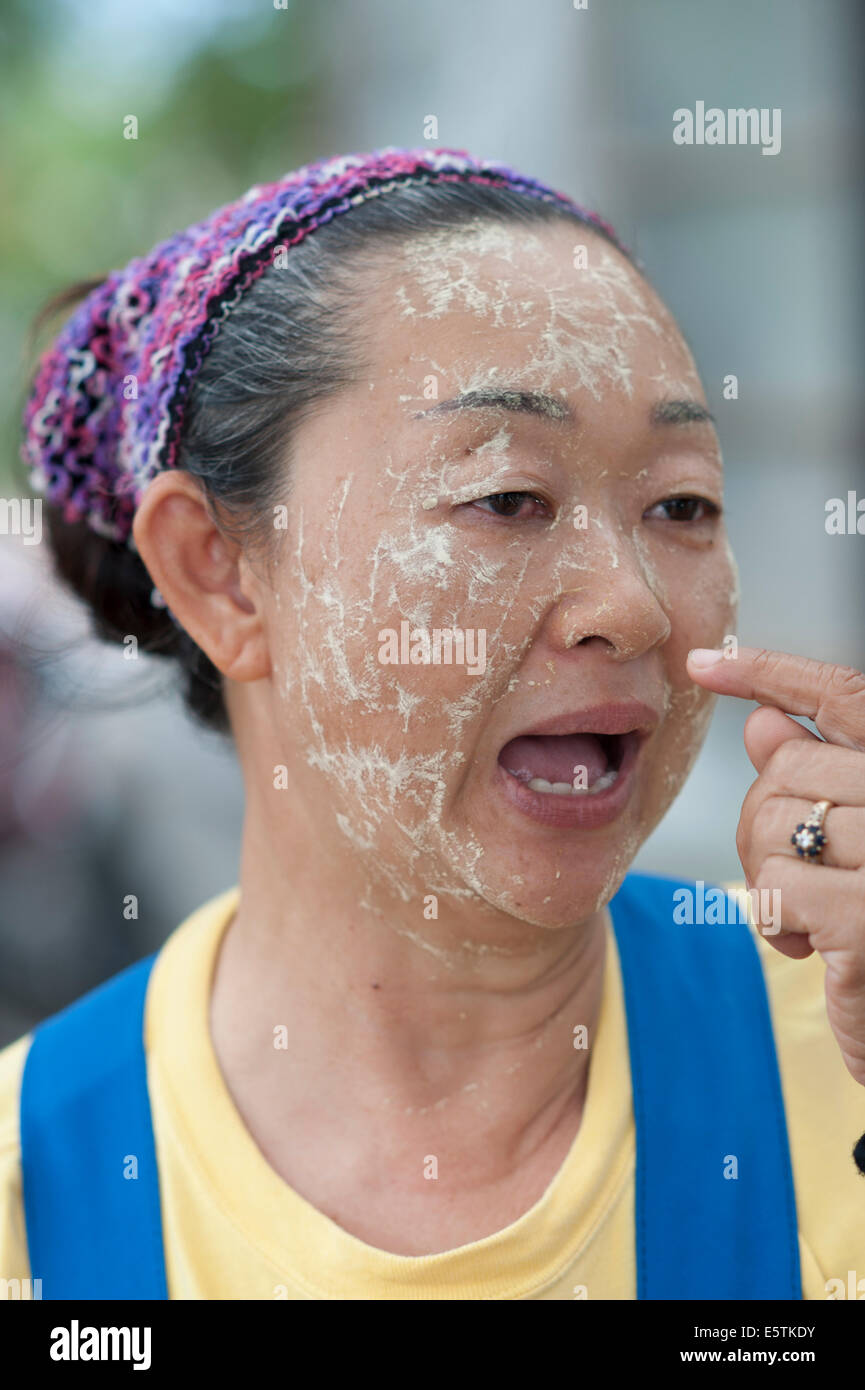 Une vieille femme thaïlandaise à l'aide d'herbes naturelles et de mélange de feuilles pour protéger son visage du soleil Banque D'Images