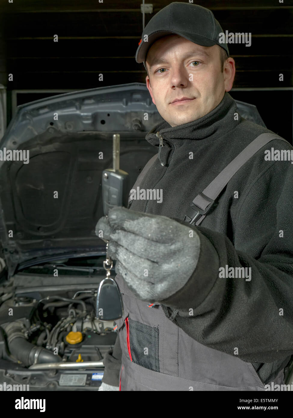 Auto mechanic holding une clé de voiture de la voiture réparée en attente d'être remis au client Banque D'Images
