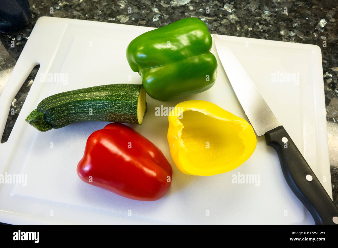 Vert, poivrons rouge et jaune avec une courgette sur une planche à découper Banque D'Images