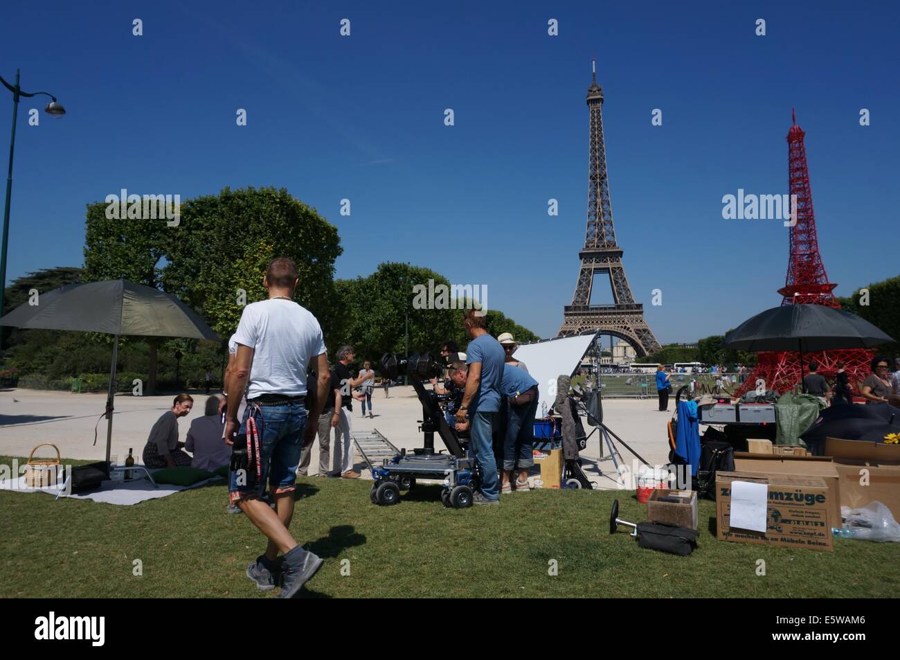 Un cast est filmer au Champ de Mars avec la Tour Eiffel contre un ciel bleu en arrière-plan Banque D'Images