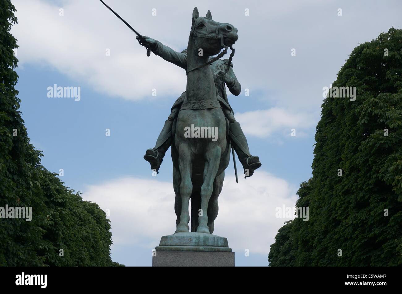 Une sculpture d'un chevalier sur un cheval contre un ciel bleu entouré d'arbres verts Banque D'Images