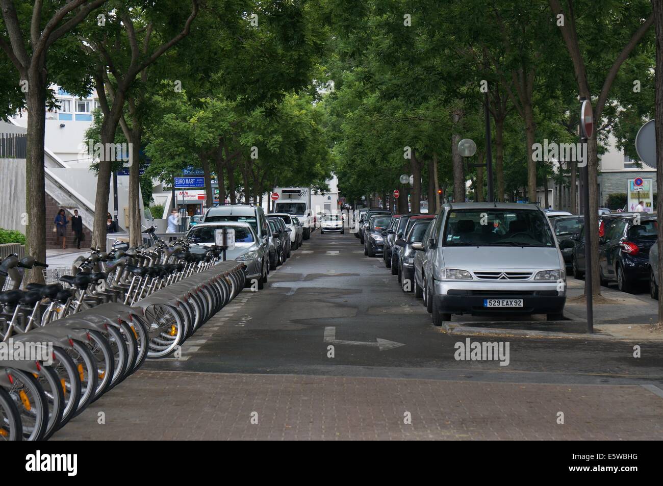 Rue de Paris, une file de voitures en stationnement sur la droite, un rack de vélo sur la gauche Banque D'Images
