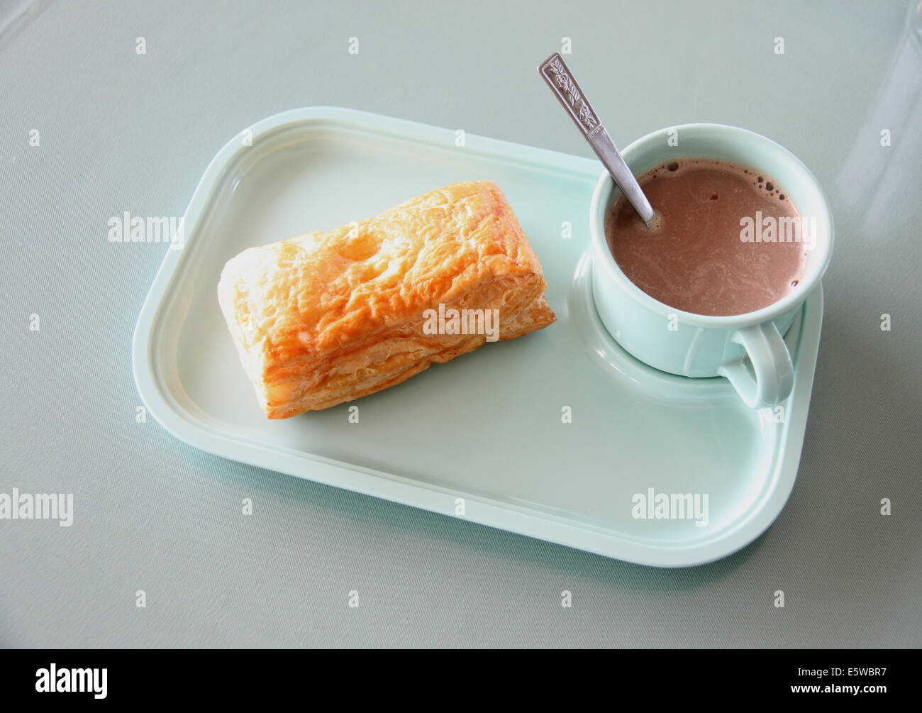 Patty et chocolat chaud dans un plat bleu sur une table à manger. Banque D'Images Patty et chocolat chaud dans un plat bleu sur une table à manger. Banque D'Images