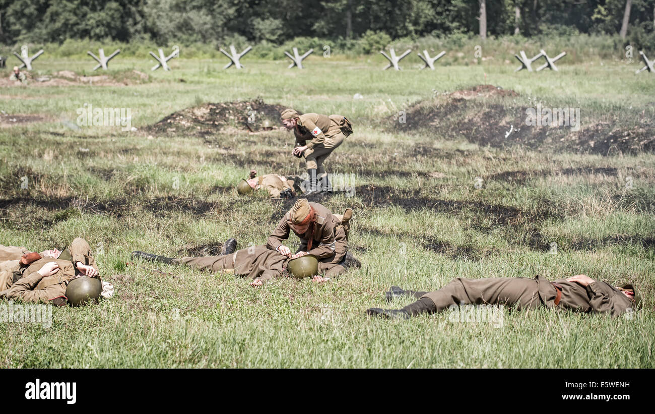 Traiter les infirmières militaires blessés sur un champ de bataille lors de la reconstruction d'une lutte de la Seconde Guerre mondiale. Banque D'Images