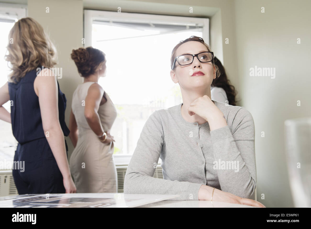Young businesswoman le regard tandis que ses collègues donnent de la fenêtre Banque D'Images