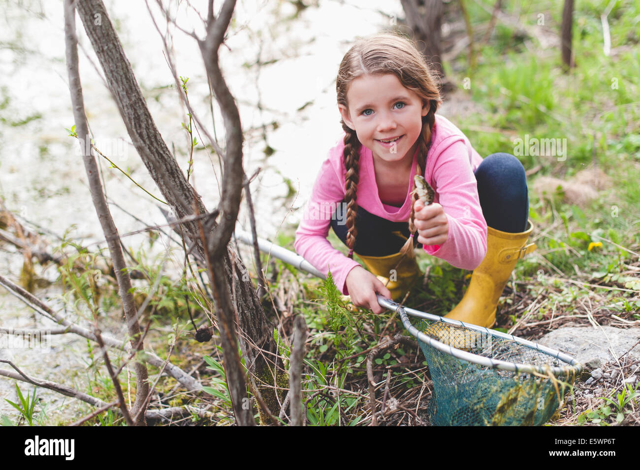 Portrait of Girl holding up frog et filet de pêche Banque D'Images