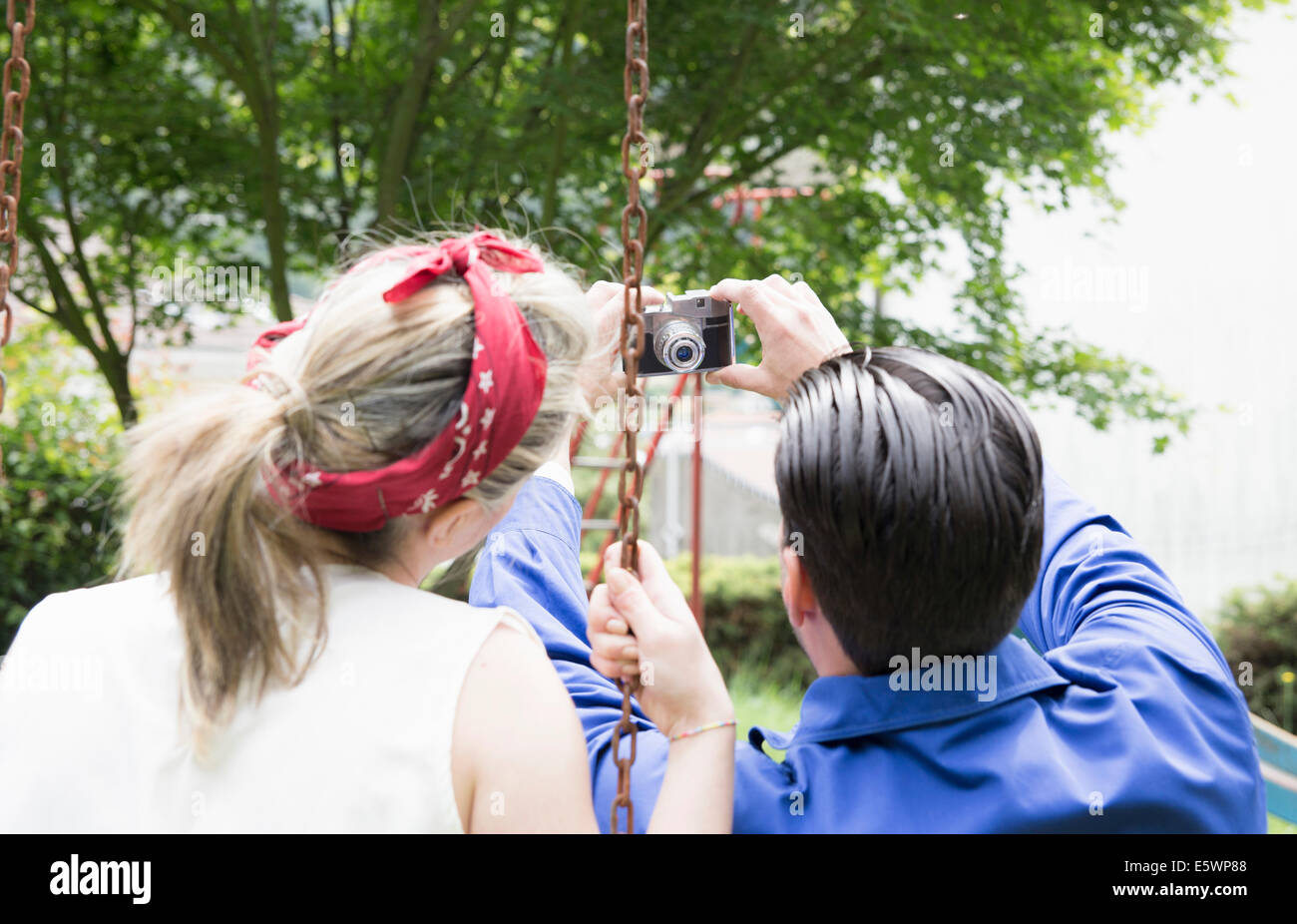 Vue arrière du jeune couple vintage avec caméra dans jardin selfies Banque D'Images