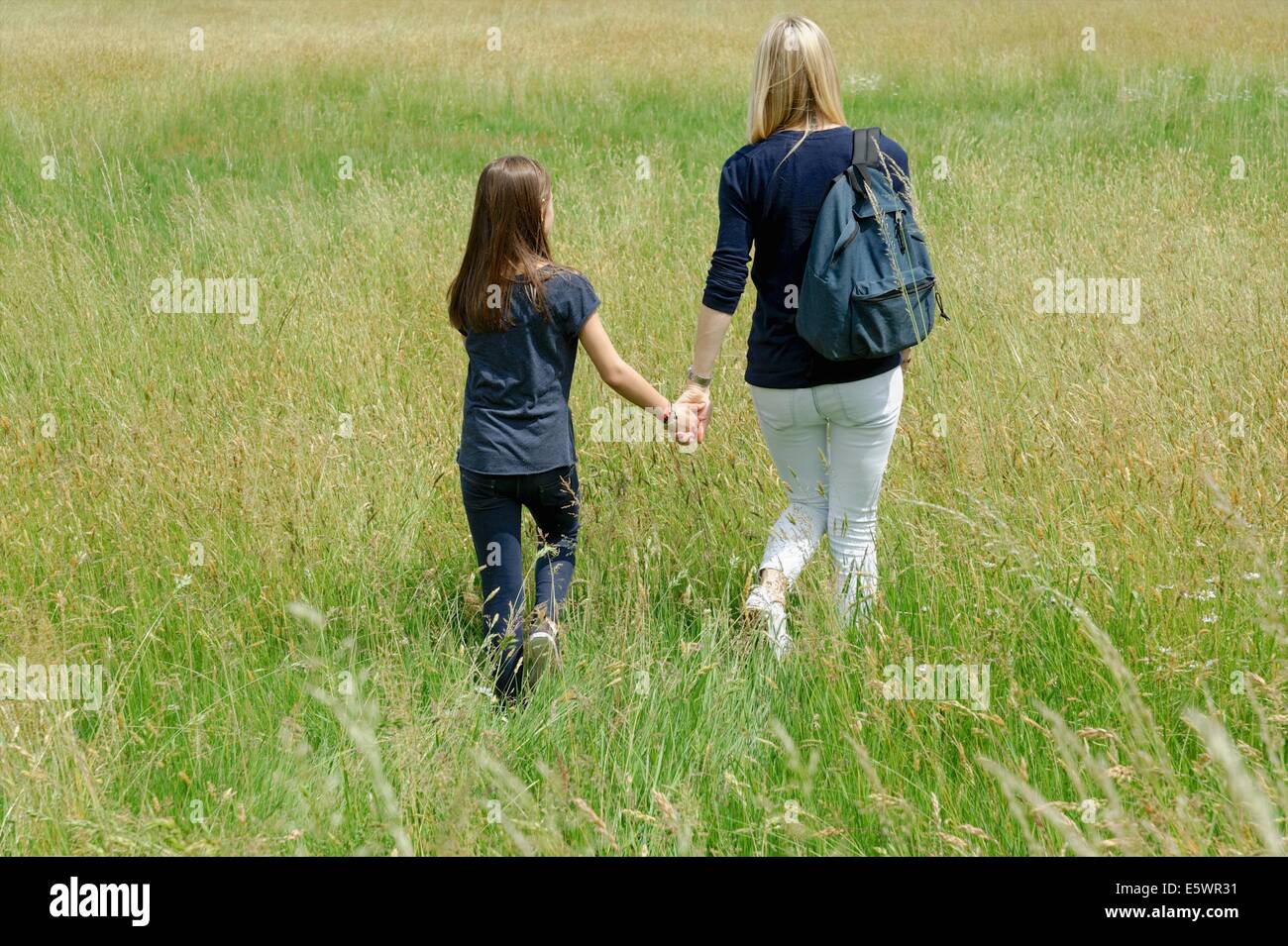 Vue arrière de la mère et la fille se baladant dans la longue herbe domaine Banque D'Images