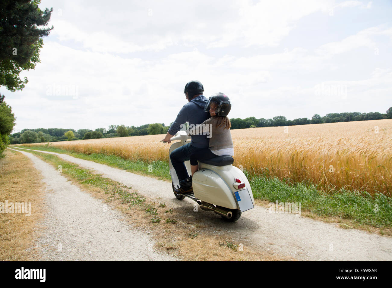 Vue arrière de l'homme mûr et sa fille équitation scooter le long chemin de terre Banque D'Images