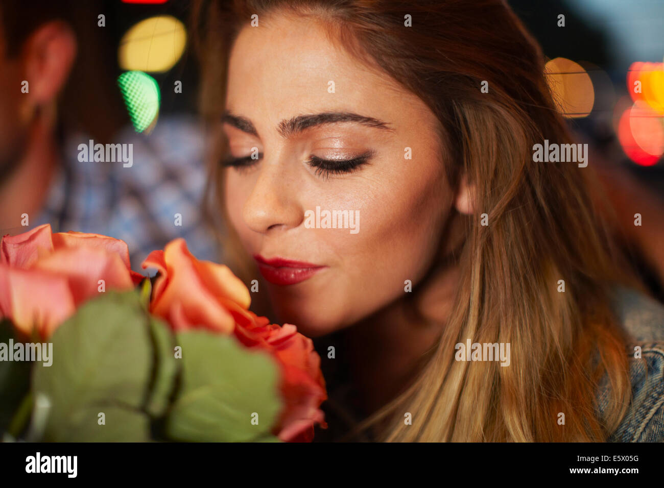 Jeune femme avec petit ami smelling roses en ville taxi la nuit Banque D'Images