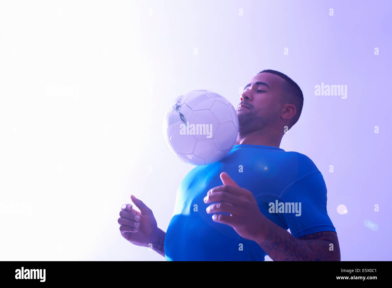 Portrait de jeune homme joueur de foot ball mid air avec maintien de la poitrine Banque D'Images