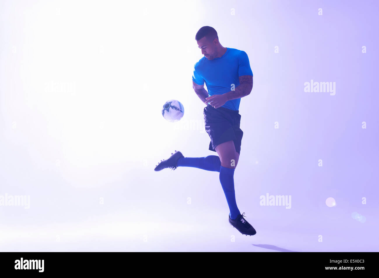 Portrait de jeune homme joueur de foot ball maintien mid air avec coup Banque D'Images