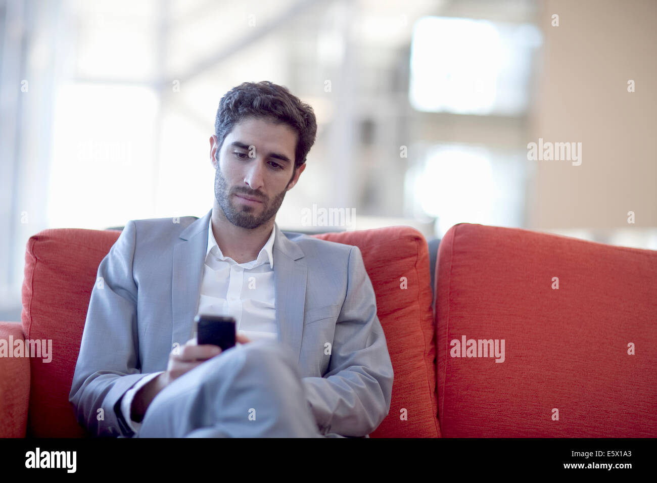 Young businessman texting on smartphone canapé dans conference centre Banque D'Images