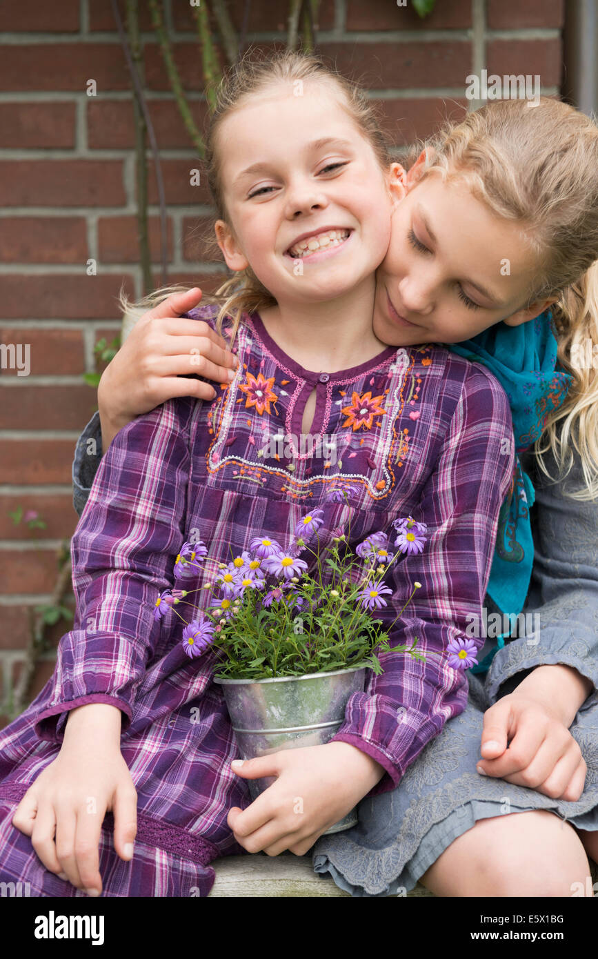 Deux soeurs avec pot de fleur plante dans jardin Banque D'Images