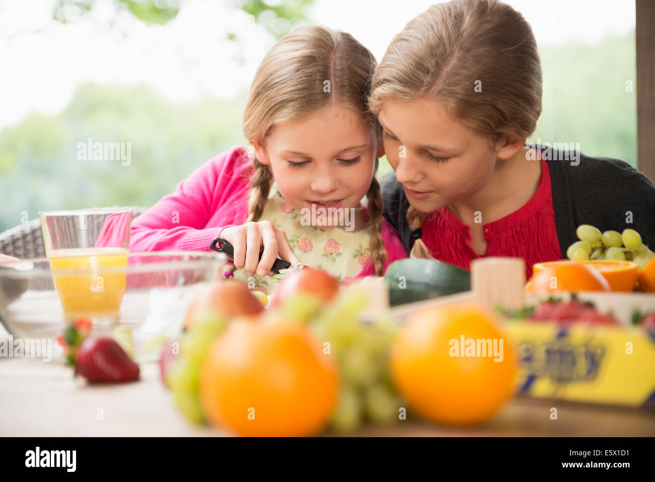 Deux soeurs à table patio apprendre à couper les fruits Banque D'Images