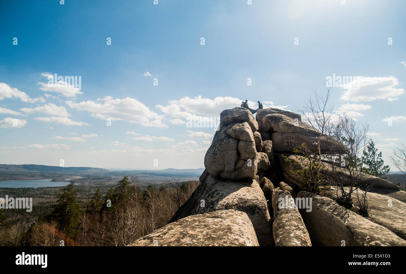 Trois randonneurs masculins sur haut de rock formation à distance dans le lac Banque D'Images