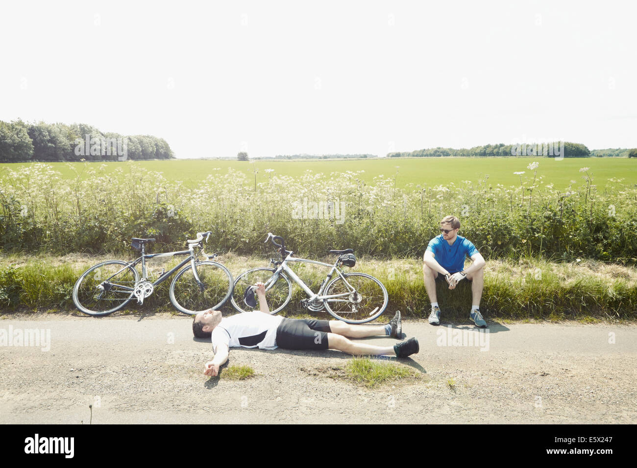 Les cyclistes étendue sur le sol de champs, Cotswolds, Royaume-Uni Banque D'Images