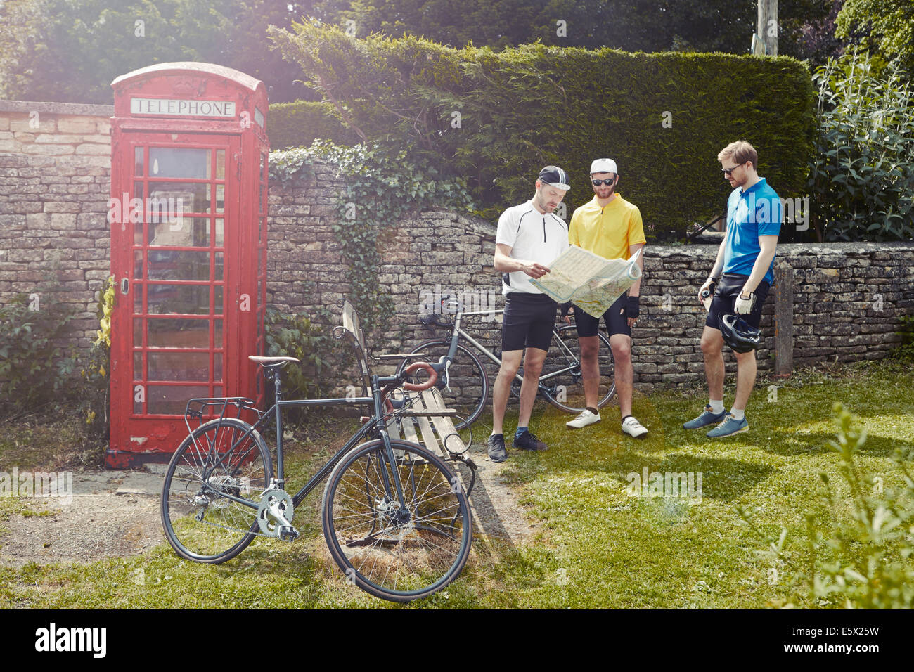 Les cyclistes lecture de carte par téléphone rouge fort, Cotswolds, Royaume-Uni Banque D'Images