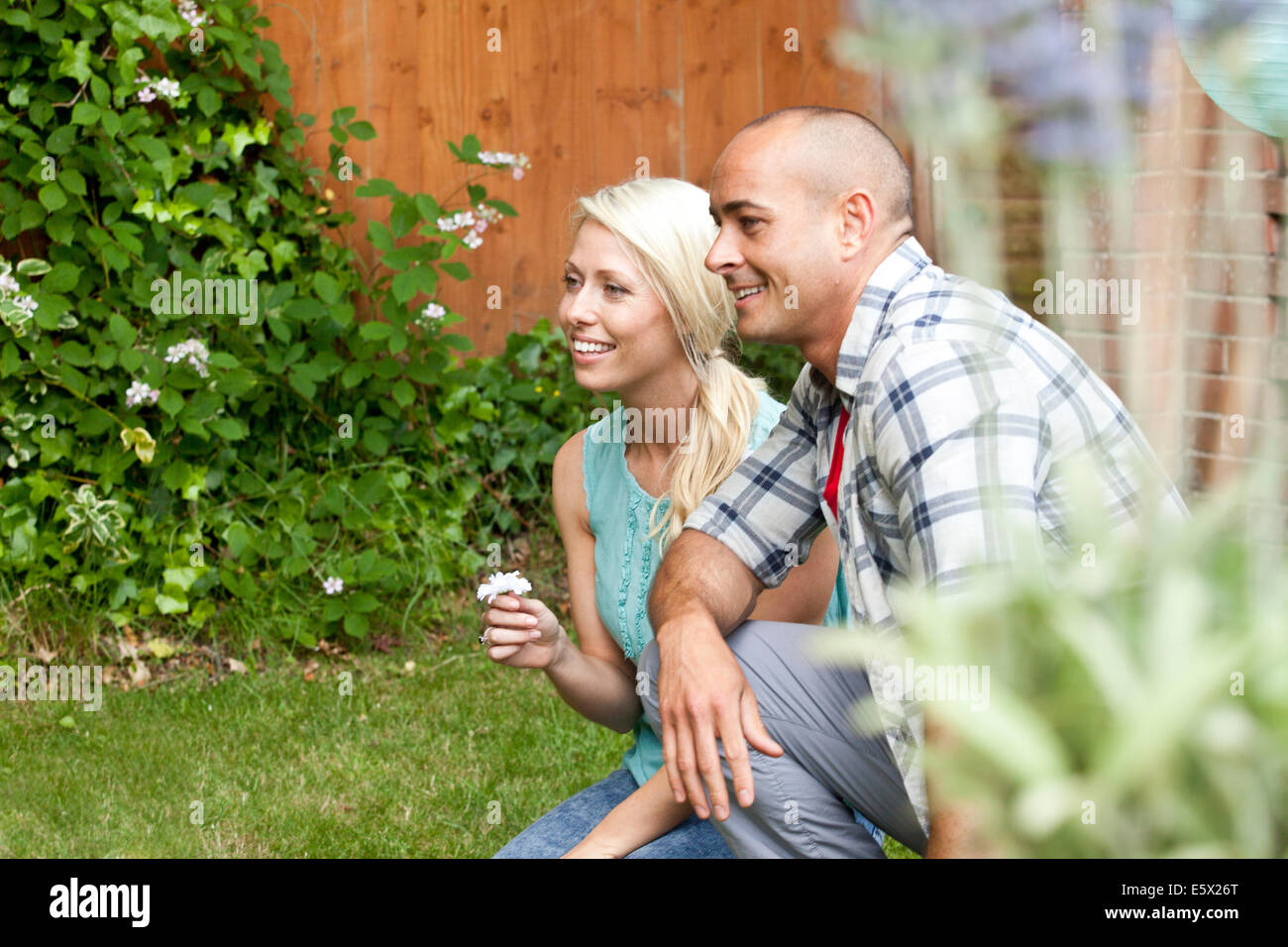 Couple accroupi en regardant le jardin Banque D'Images