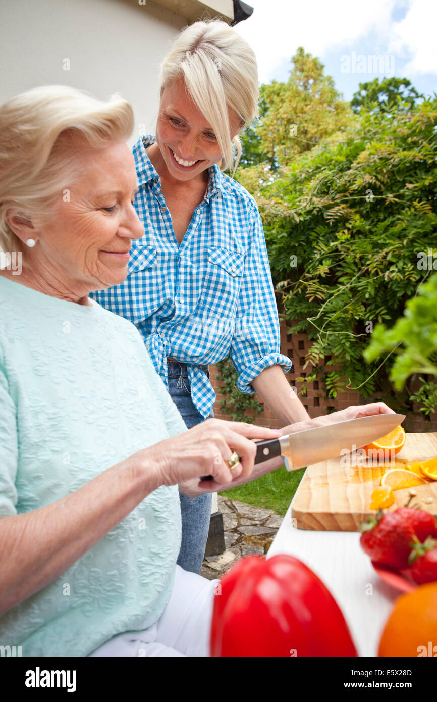 Grand-mère et petite-fille de discuter tout en préparant la nourriture à table de jardin Banque D'Images Grand-mère et petite-fille de discuter tout en préparant la nourriture à table de jardin Banque D'Images
