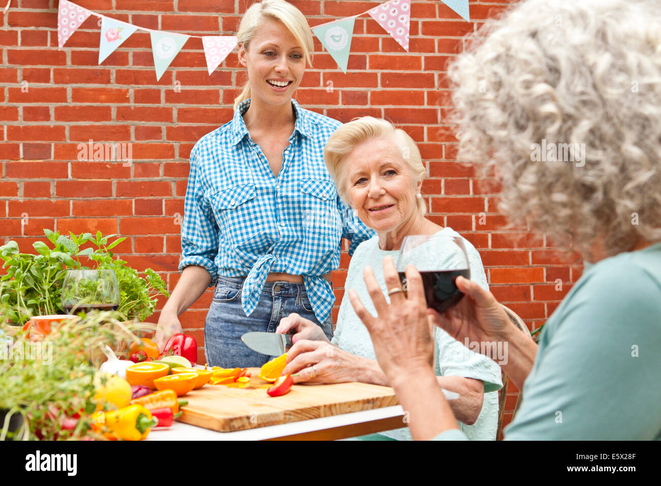 Trois génération women chatting durant la préparation d'aliments à table de jardin Banque D'Images Trois génération women chatting durant la préparation d'aliments à table de jardin Banque D'Images