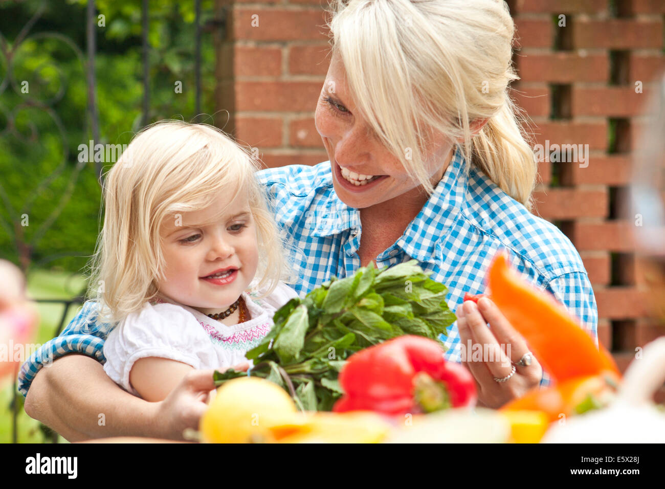 Mère et enfant fille de préparer des aliments à table de jardin Banque D'Images Mère et enfant fille de préparer des aliments à table de jardin Banque D'Images