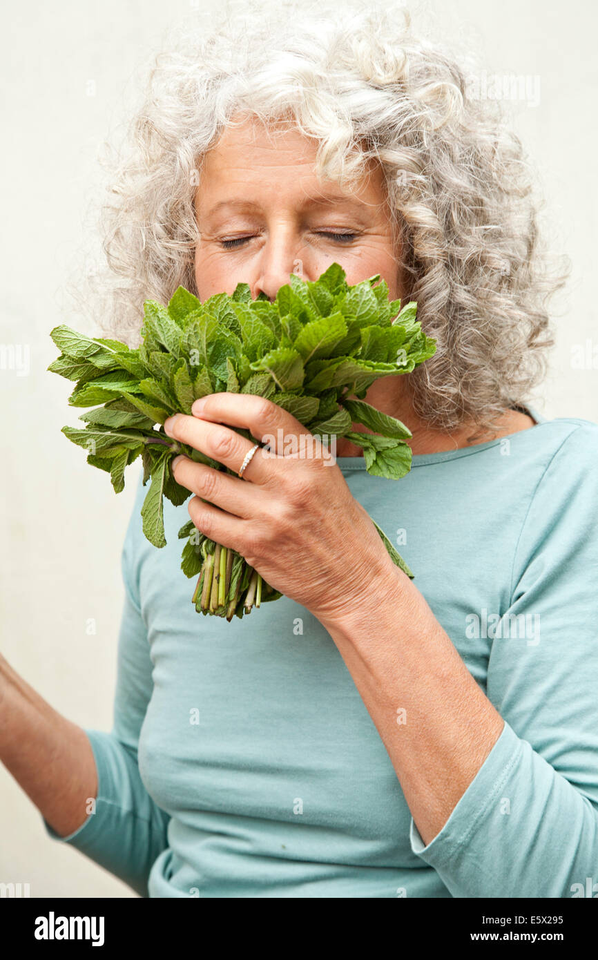 Young woman smelling bouquet de menthe dans le jardin Banque D'Images