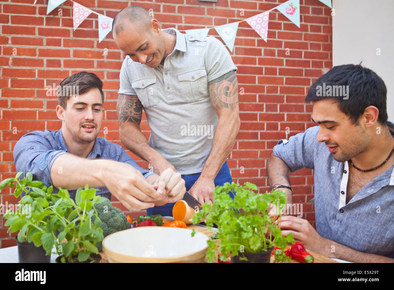 Trois amis à hacher et de préparer des aliments pour jardin barbecue Banque D'Images
