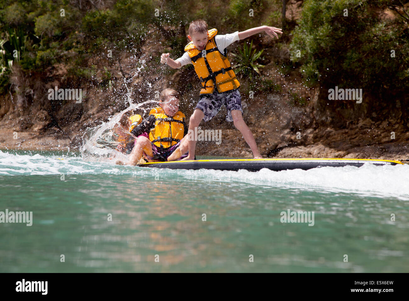 Frères et soeur splashing from paddleboard en mer Banque D'Images