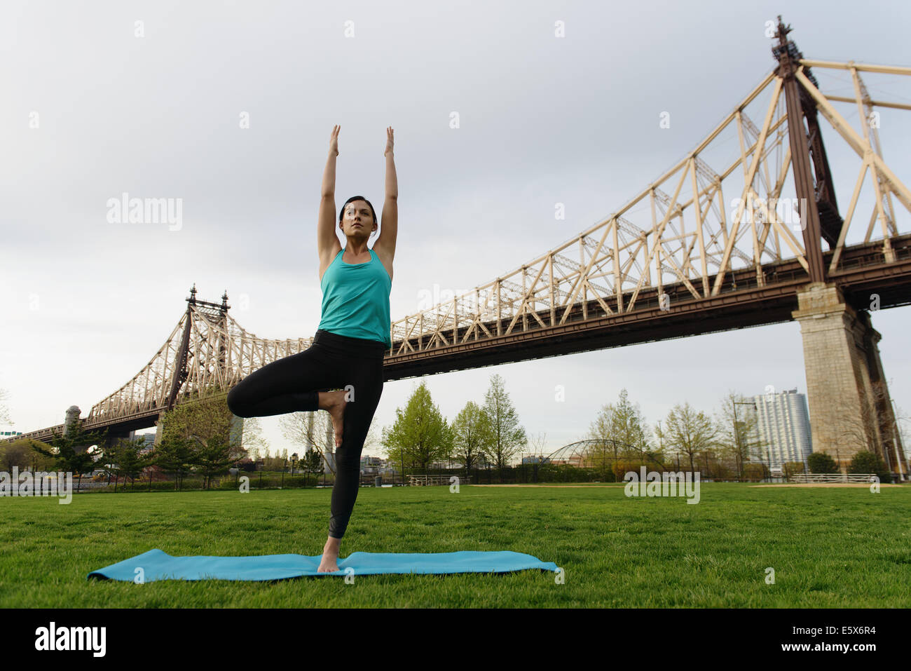 Young woman practicing yoga posture de l'arbre dans le parc de la ville Banque D'Images