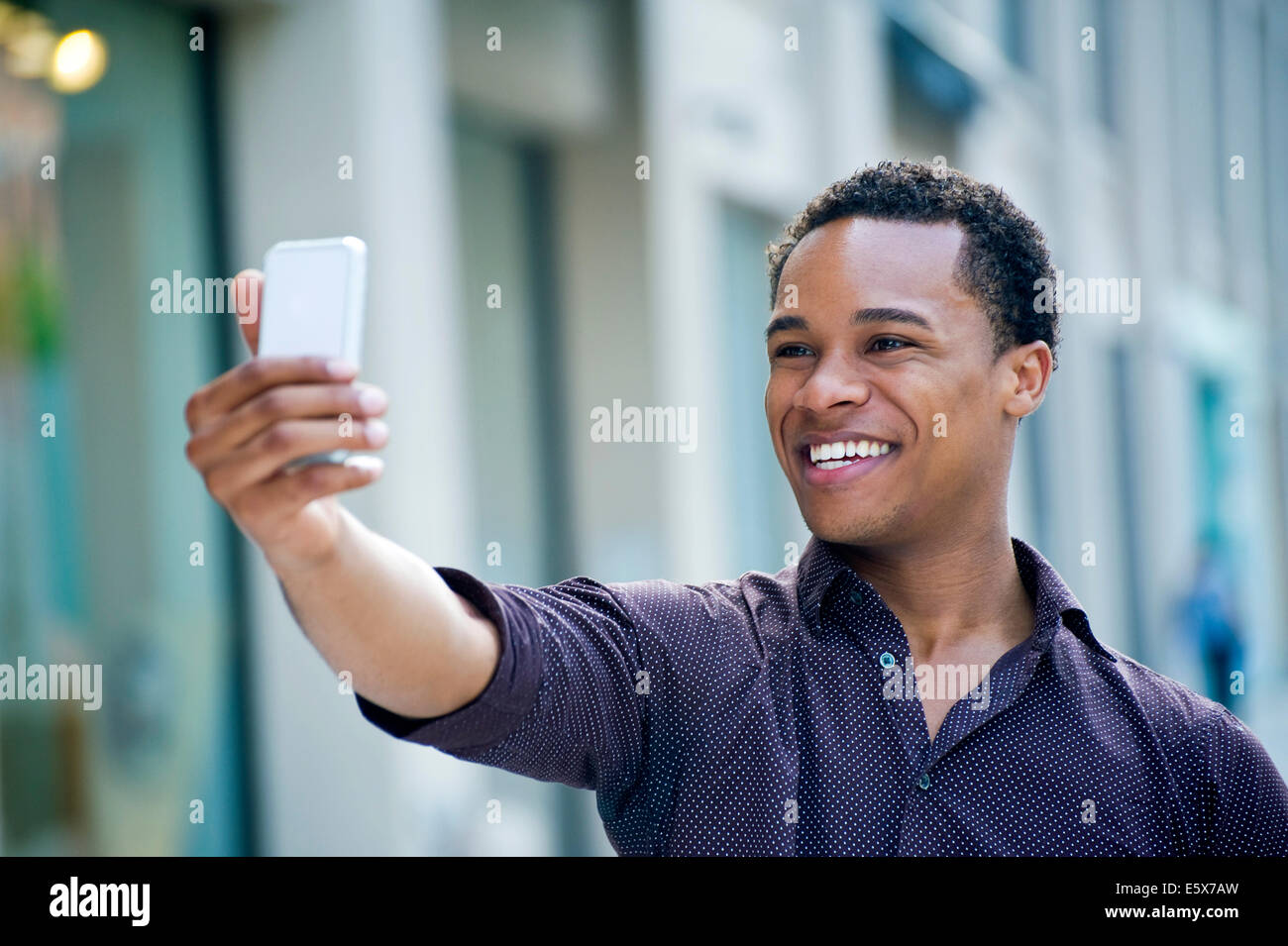 Jeune homme en tenant selfies smartphone on city street Banque D'Images