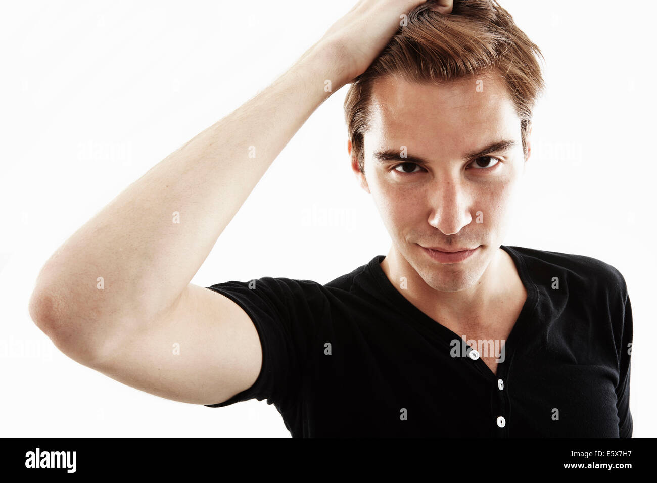 Studio portrait of young man with hand in hair Banque D'Images