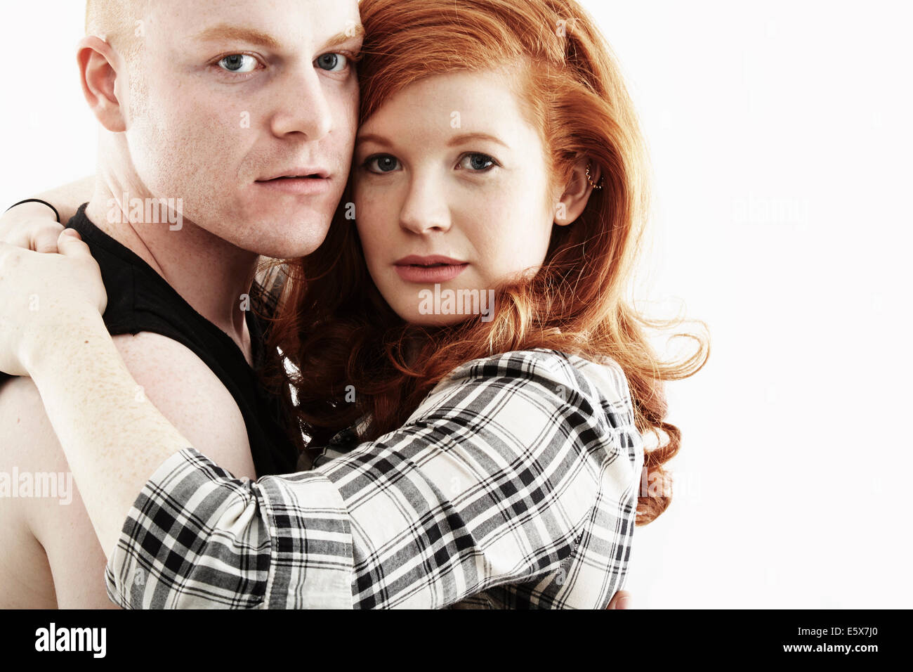 Studio portrait of red haired young couple hugging joue contre joue Banque D'Images