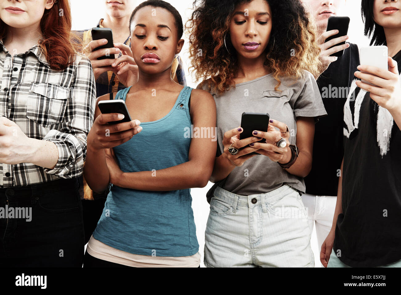Portrait de six jeunes adultes texting on smartphone Banque D'Images