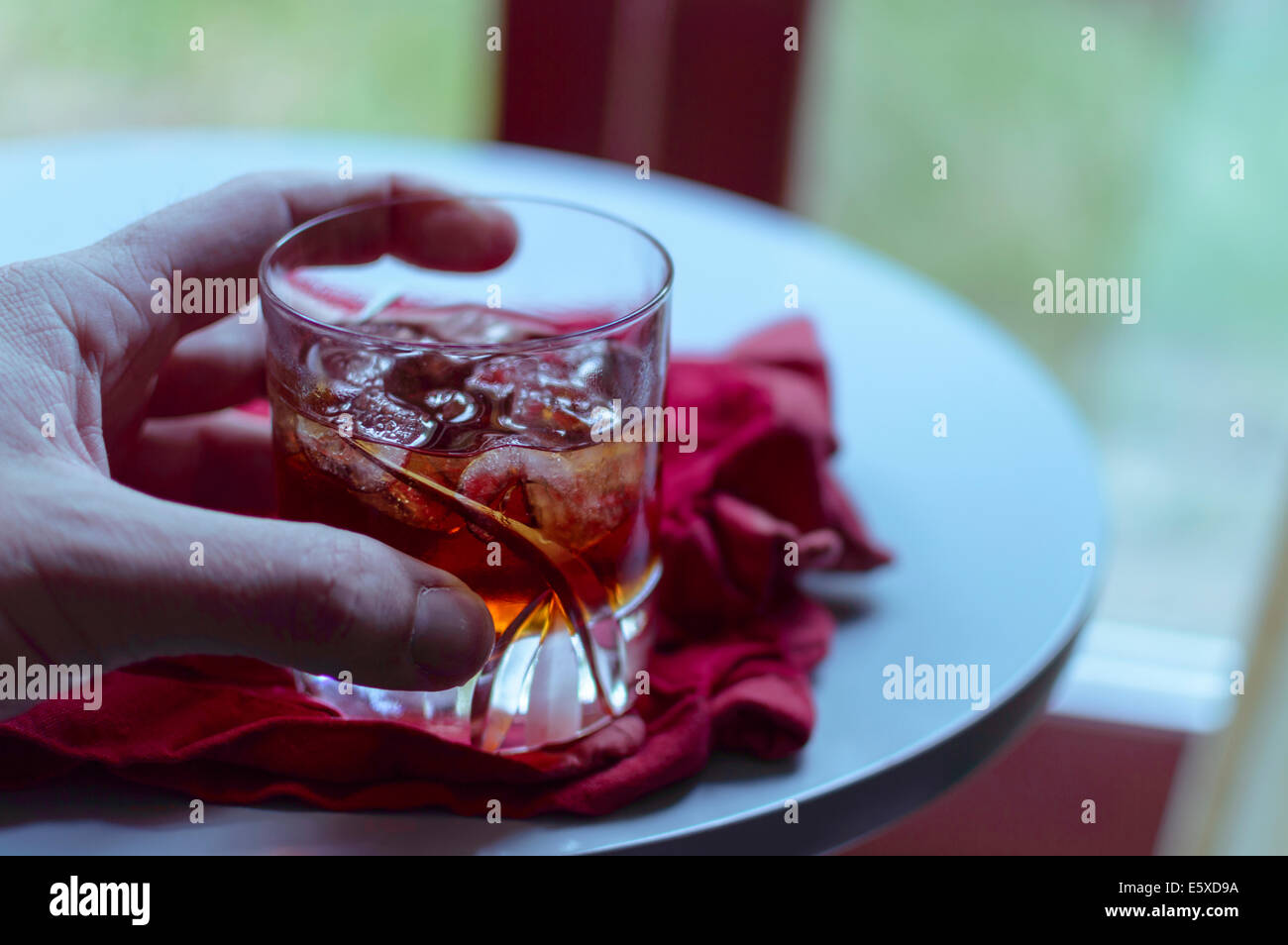 Un verre d'amaretto avec de la glace tenu par une main Banque D'Images