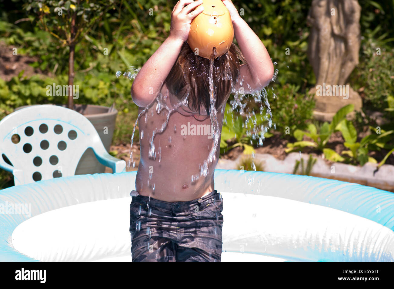 Jeune garçon verser de l'eau sur la tête pour se rafraîchir par une chaude journée Banque D'Images