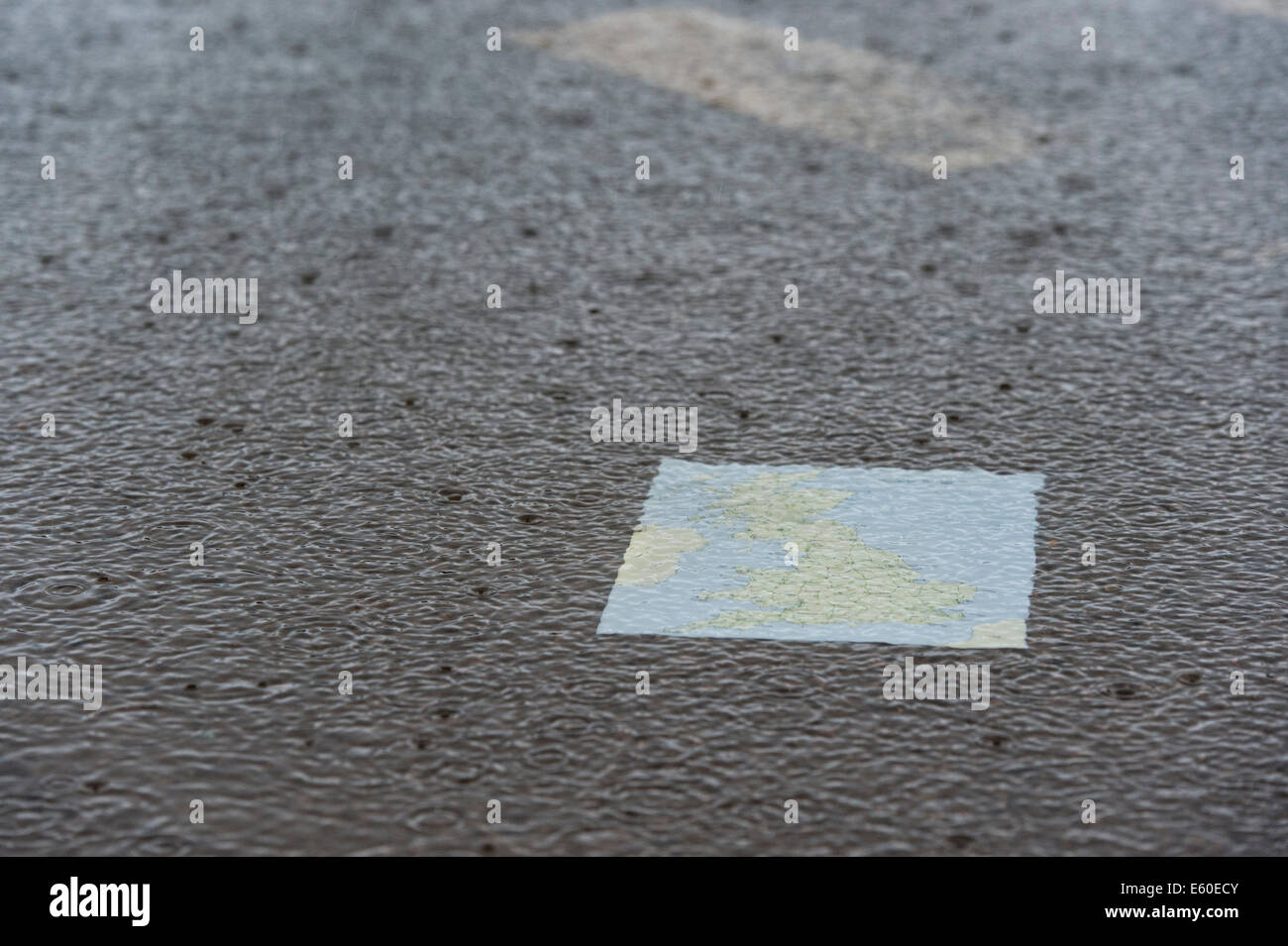 La carte du Royaume-Uni dans une flaque d'eau sur une route sous la pluie. Banque D'Images
