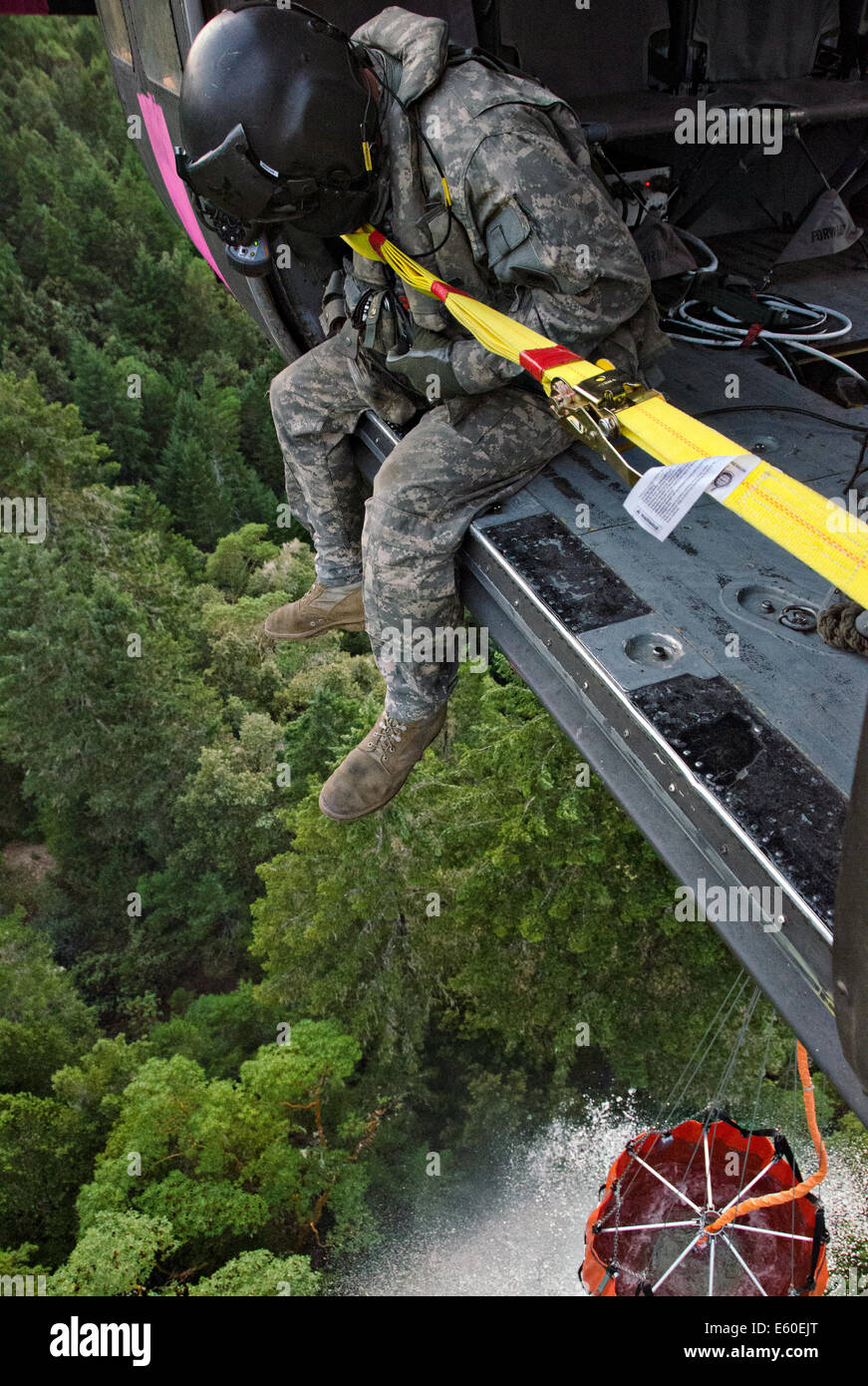 Un soldat américain dans un UH-60 Black Hawk recueille de l'eau dans un seau bambi incendie le 4 août 2014 dans le comté de Mendocino, en Californie. Banque D'Images